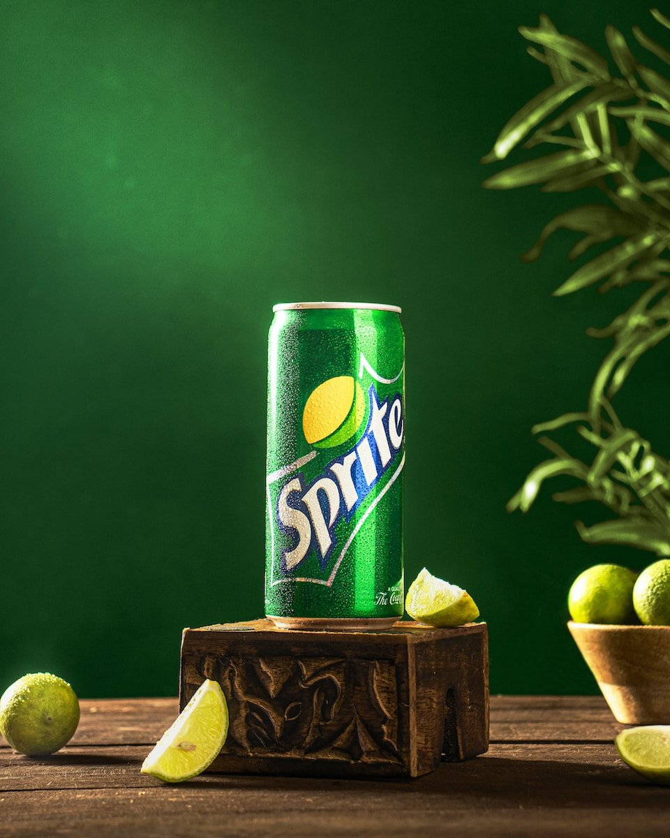 a can of sprite on a wooden stand with limes